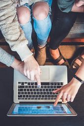 three people sitting down pointing at a laptop