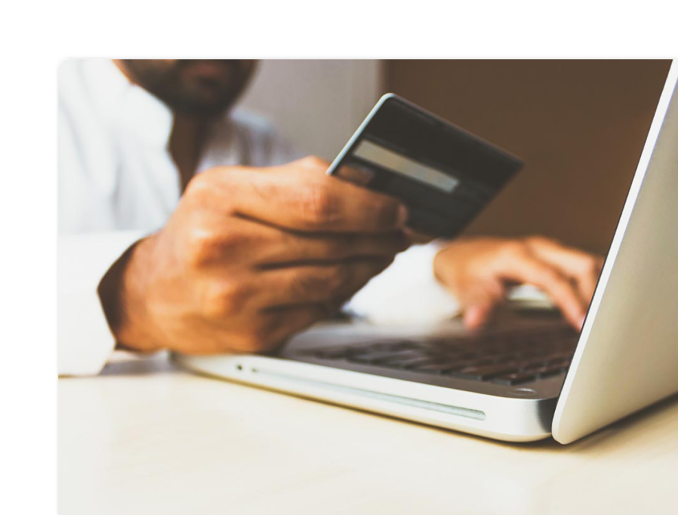 a man holding a credit card ordering something online with a laptop in front of him