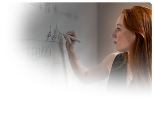 red haired woman writing on white board the initial layout of the flagstaff website design