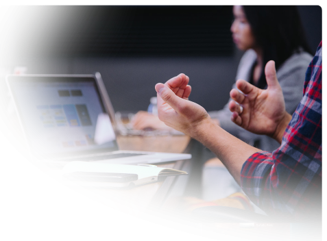 two people discussing a project at a table pointing to our flagstaff website design team – faded on left and bottom
