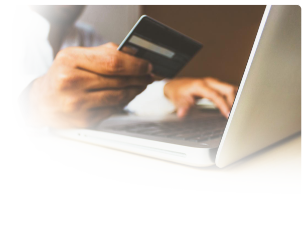 a man holding a credit card ordering something online with a laptop in front of him