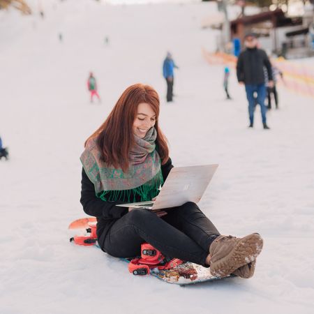 woman sitting in the snow on a laptop at arizona snowbowl in flagstaff